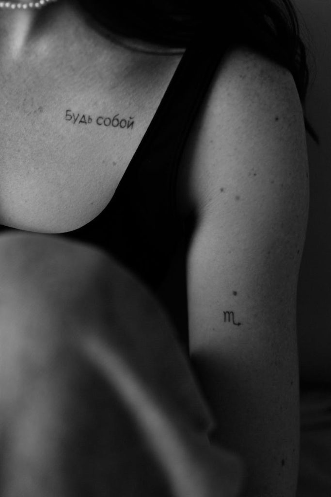Artistic black and white photo capturing detailed tattoos on human skin.
