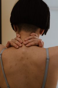 Close-up of a person with short hair, hands on neck, creating a thoughtful mood.