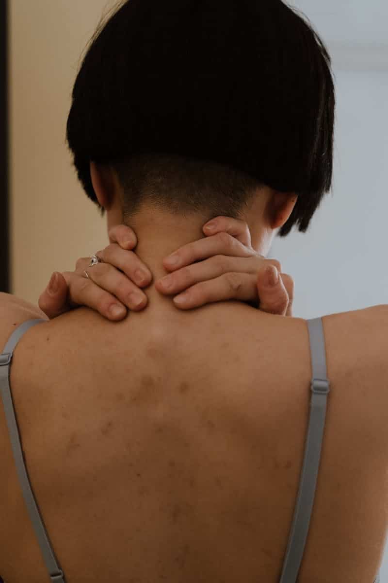 Close-up of a person with short hair, hands on neck, creating a thoughtful mood.